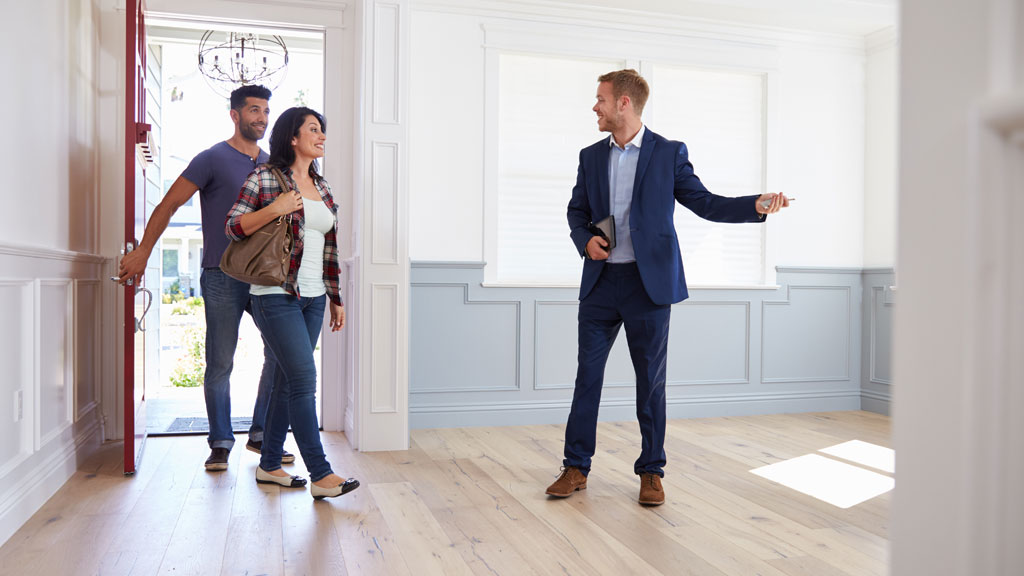 Acquéreur inspectant la qualité des fenêtres lors d'une visite immobilière